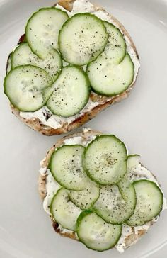 two pieces of bread with cucumbers on them sitting on a plate next to each other