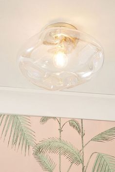 a light that is on the ceiling in a room with pink walls and palm trees