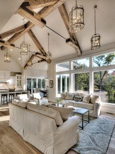 a living room filled with furniture and lots of windows next to a wooden flooring area