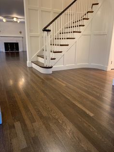 an empty living room with hardwood floors and white railings on the wall, along with a staircase