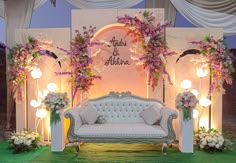 a couch sitting in front of a white wall with flowers on it and an arch