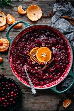 a pot filled with cranberry sauce and topped with an orange slice, cinnamon sticks