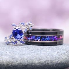 Introducing the Cornflower Sapphire & Galaxy Orion Nebula Couples Ring Set, a mesmerizing duo designed to celebrate your celestial bond. This His and Hers ring set features bands adorned with striking cornflower sapphires and galaxy-inspired details, reminiscent of the breathtaking Orion Nebula. The vivid blue of the sapphires perfectly complements the cosmic artistry of the design, creating a harmonious blend of elegance and otherworldly beauty. These rings are a perfect symbol of your shared journey and eternal connection, making them an ideal choice for couples who seek a unique and meaningful expression of their love. ►Sold as a two-piece set ►His ring is Black Tungsten Carbide with Crushed Purple Fire Opal Inlay.  ►Her ring is 925 solid sterling silver with rhodium finish.  ►Her Band Purple Promise Rings For Couples, Fusion Style Promise Ring With Accent Stones, Fusion Style Sapphire Jewelry For Anniversary, Blue Fusion Style Wedding Rings, Blue And Purple Wedding Rings, Galaxy Ring Engagement, Fusion Style Multi-stone Wedding Rings, Galaxy Wedding Ring, Black Multi-stone Wedding Rings