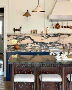 a kitchen with marble counter tops and stools