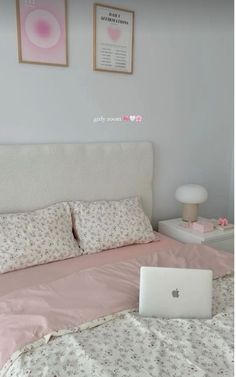 a laptop computer sitting on top of a bed next to two pictures above the headboard