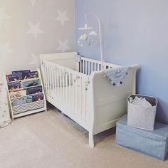 a baby's room with blue walls and white furniture