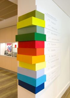 a stack of colorful papers on a wall in an office building with wood flooring