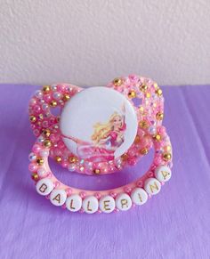 a close up of a hair clip on a purple surface with gold and pink beads