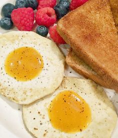 two fried eggs, toast and berries on a plate