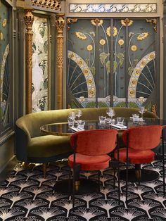 an elegant dining room with red chairs and gold accents on the walls, along with art deco - inspired wallpaper