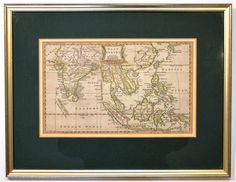 an old map is hanging on the wall in front of a black frame with gold trim