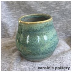 a green vase sitting on top of a gray cloth