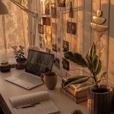 an open laptop computer sitting on top of a desk next to a potted plant