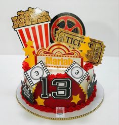 a red and white birthday cake with movie themed decorations on the top, including popcorn