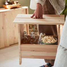 a person standing in front of a wooden table holding a tray with food and drinks