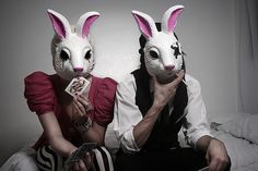 two people wearing bunny ears sitting on a bed with cards in front of their faces