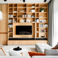 a living room filled with furniture and a flat screen tv mounted on a wall next to a window