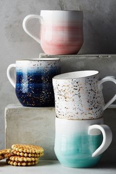 three coffee mugs sitting next to each other on top of a shelf with corn cobs