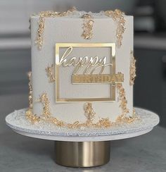 a white and gold happy birthday cake on a table