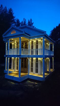 a large white house with lights on it's windows and balconies at night