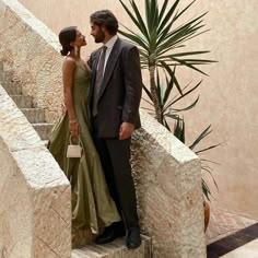 a man and woman are standing on the stairs together in front of a palm tree