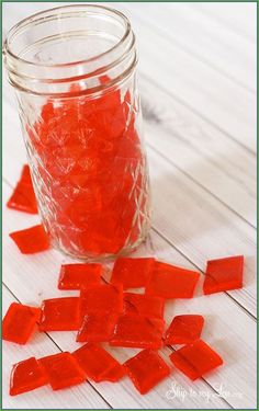 a jar filled with red gummy bears sitting on top of a white wooden table