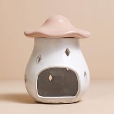 a white ceramic object with a pink hat on it's head and eyes, sitting on a table