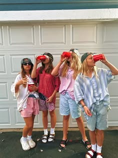 three girls standing in front of a garage door looking through binoculars