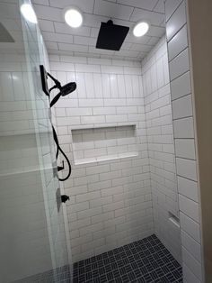 a walk in shower sitting next to a white tiled wall with black grouting