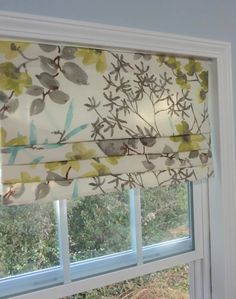 a window with a flowered valance and matching shades on it's windowsill