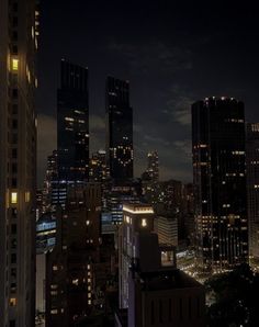 the city skyline is lit up at night with skyscrapers in the foreground and clouds in the background