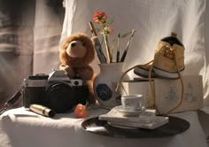 a teddy bear sitting on top of a table next to a camera and other items