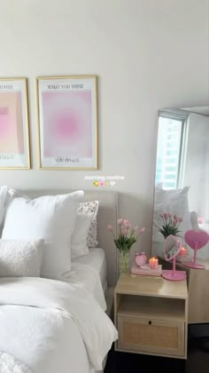 a bed with white sheets and pillows in a bedroom next to two pictures on the wall