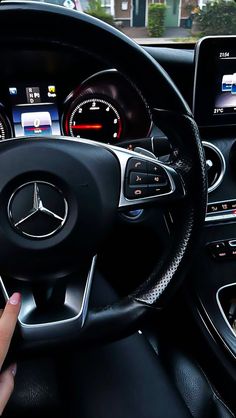 a person driving a car with their hand on the steering wheel and dashboard screen showing