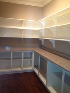 an empty kitchen with white cabinets and marble counter tops in the corner, along with hard wood flooring