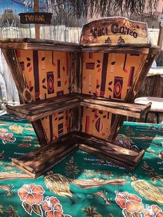 an open wooden box sitting on top of a table covered in green and orange cloth