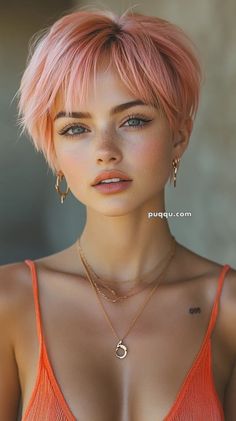 a young woman with pink hair and piercings wearing an orange top is looking at the camera