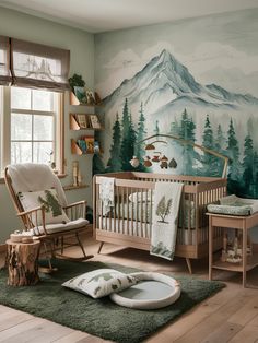 a baby's room decorated in green and white with mountains painted on the wall