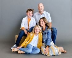 a family posing for a photo in front of a gray background