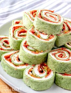 a plate filled with rolls covered in green and red sauce