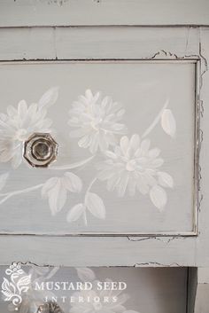 an old white painted dresser with flowers on it