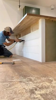 a man is using a power drill on the floor in a room with unfinished walls