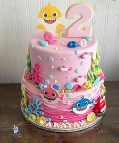 a birthday cake with pink frosting and colorful decorations on the top is decorated like a shark