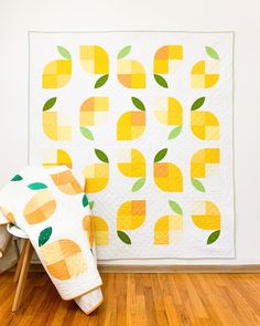 an orange and white quilt sitting on top of a wooden floor next to a chair