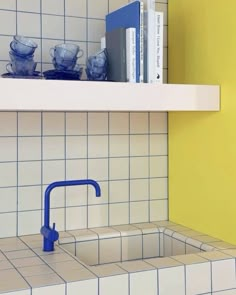 a kitchen with yellow walls and white tile on the counter top, blue handles to pull out