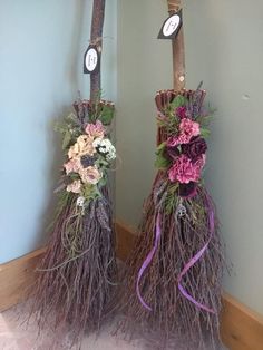 two brooms decorated with flowers and branches are sitting on the floor next to each other