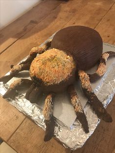 a cake shaped like a spider sitting on top of aluminum foil covered in icing