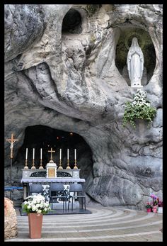 an altar with candles and flowers in front of a rock formation