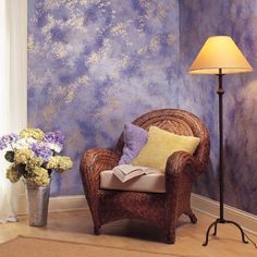 a chair and lamp in front of a blue wall with flowers on the floor next to it