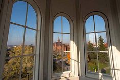 three windows in a room with the view of a city and trees from inside them